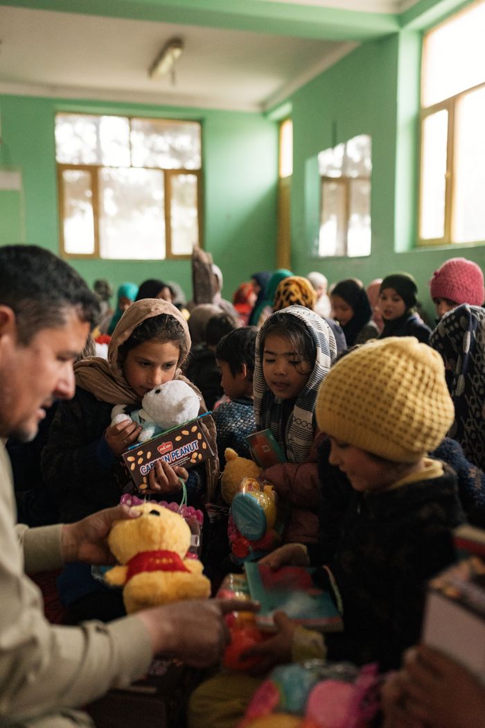 Children in Afghanistan enjoy receiving toys in a bright indoor setting, fostering joy and cultural connection.